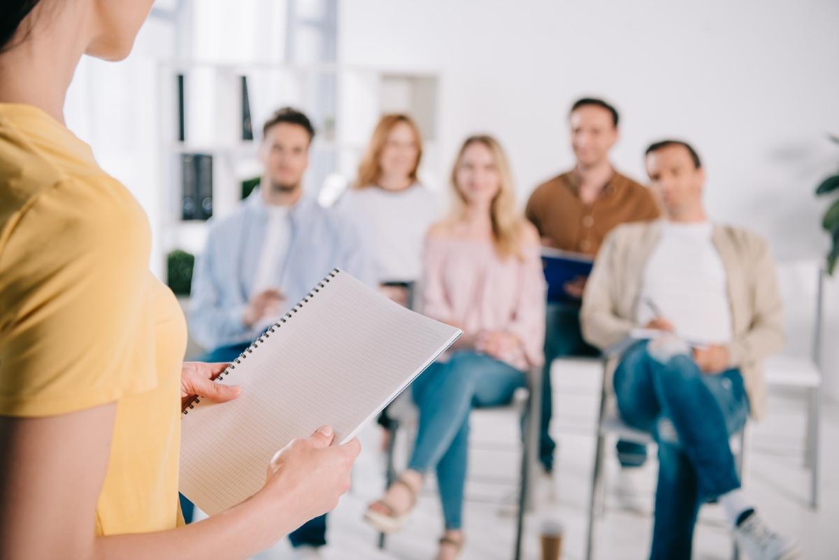 Frau referiert vor einer Gruppe sitzender junger Menschen
