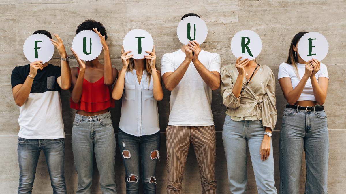Gruppe von sechs nebeneinander stehender Menschen hält Buchstaben in die Luft, die das Wort Future bilden.