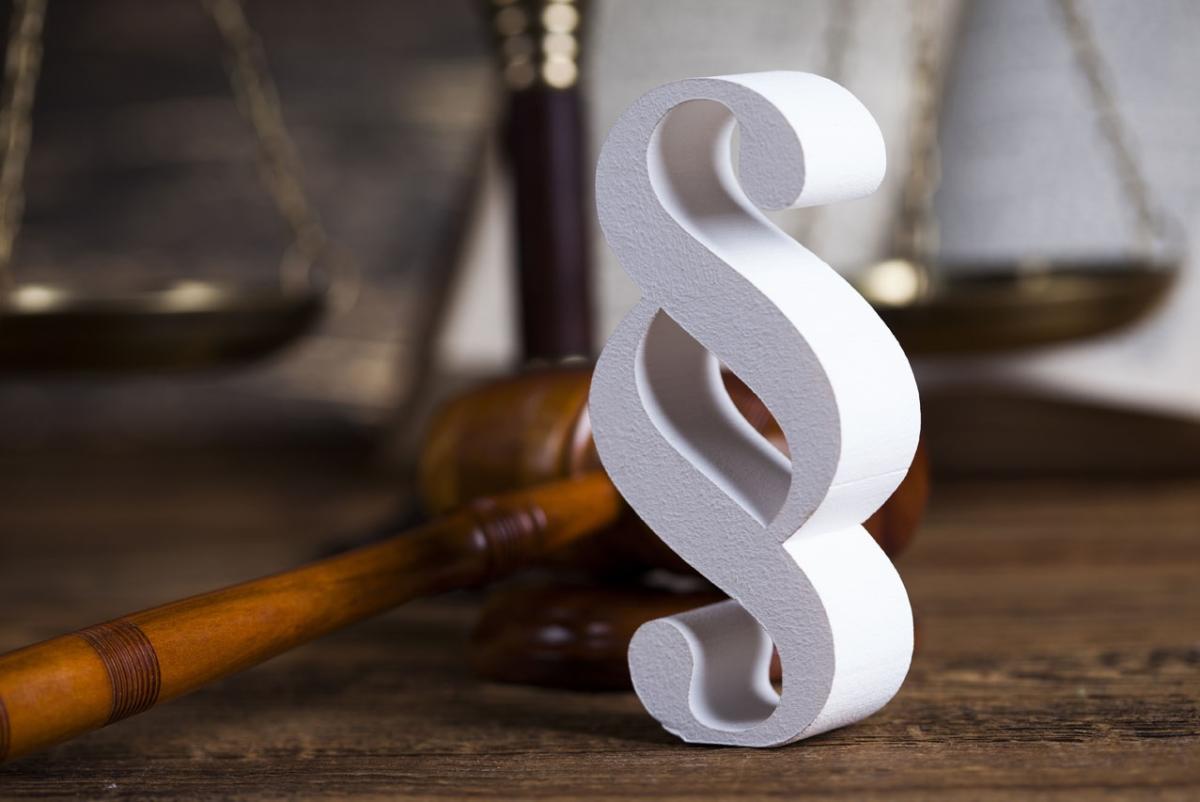 Paragraphenzeichen vor Holzhammer und Waage