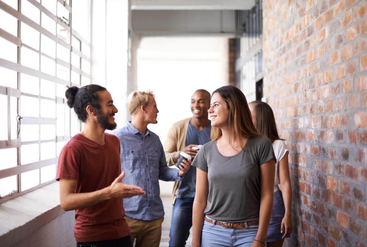 Eine diverse Gruppe junger Menschen unterhält sich freundlich 