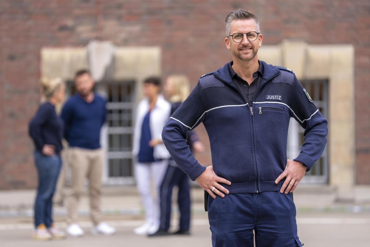 Hauptwerkmeister im Justizvollzug vor einer Gruppe von Mitarbeiter/-innen