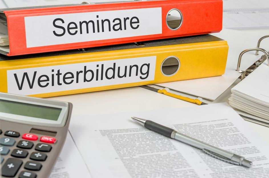 Zwei Ordner mit der Beschriftung "Seminare", "Weiterbildung" und Taschenrechner