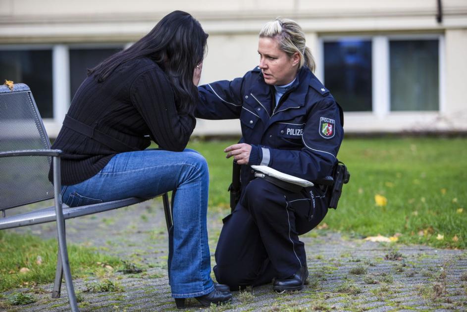 Polizistin kniet vor einer Frau