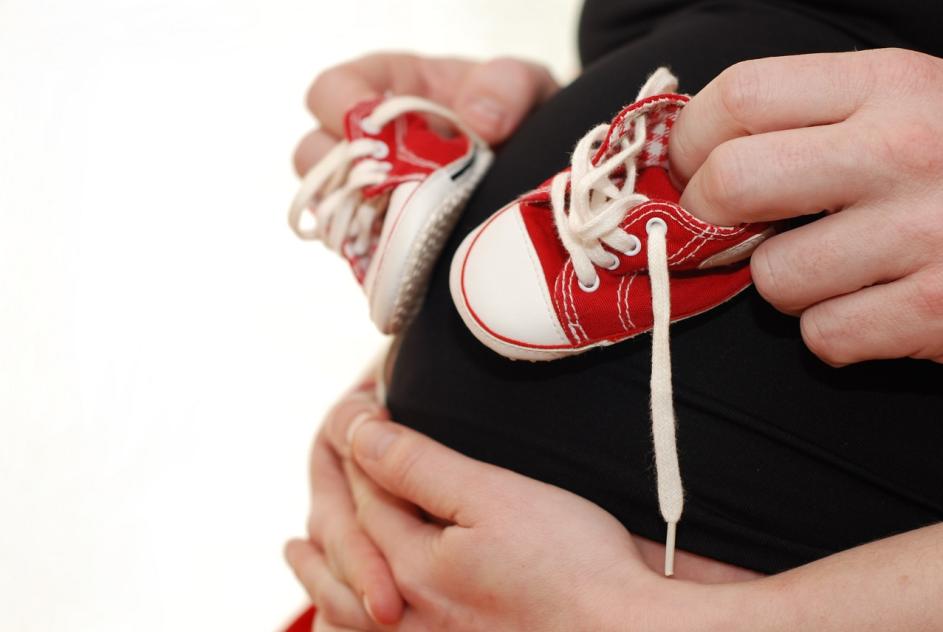 Babyschuhe auf einem Babybauch