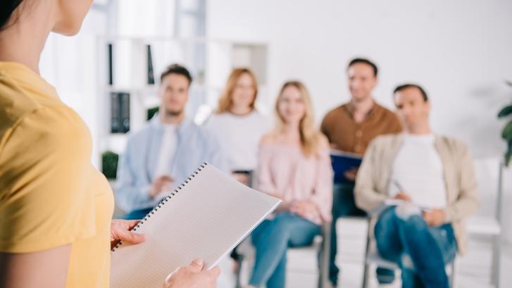 Frau referiert vor einer Gruppe sitzender junger Menschen
