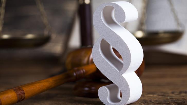 Paragraphenzeichen vor Holzhammer und Waage