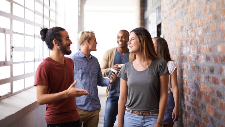 Eine diverse Gruppe junger Menschen unterhält sich freundlich 