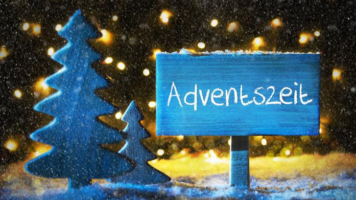 Miniaturschild und -tannenbaum aus Holz mit Schriftzug Adventszeit und Lichtern im Hintergrund