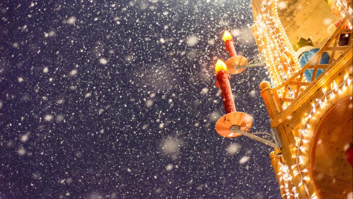 Ausschnitt eines Adventsbogens mit Kerzen und Schneefall bei Dämmerung