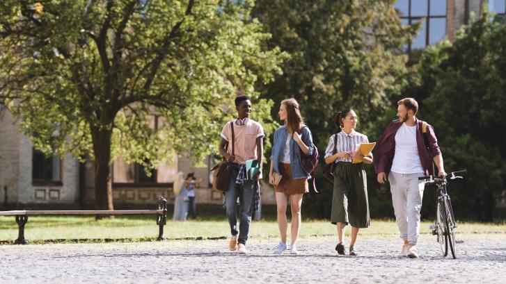 Diverse Gruppe junger Menschen läuft über Campus 