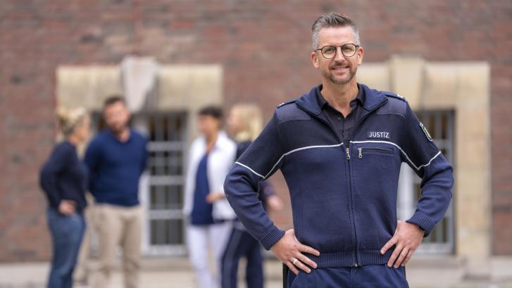 Hauptwerkmeister im Justizvollzug vor einer Gruppe von Mitarbeiter/-innen